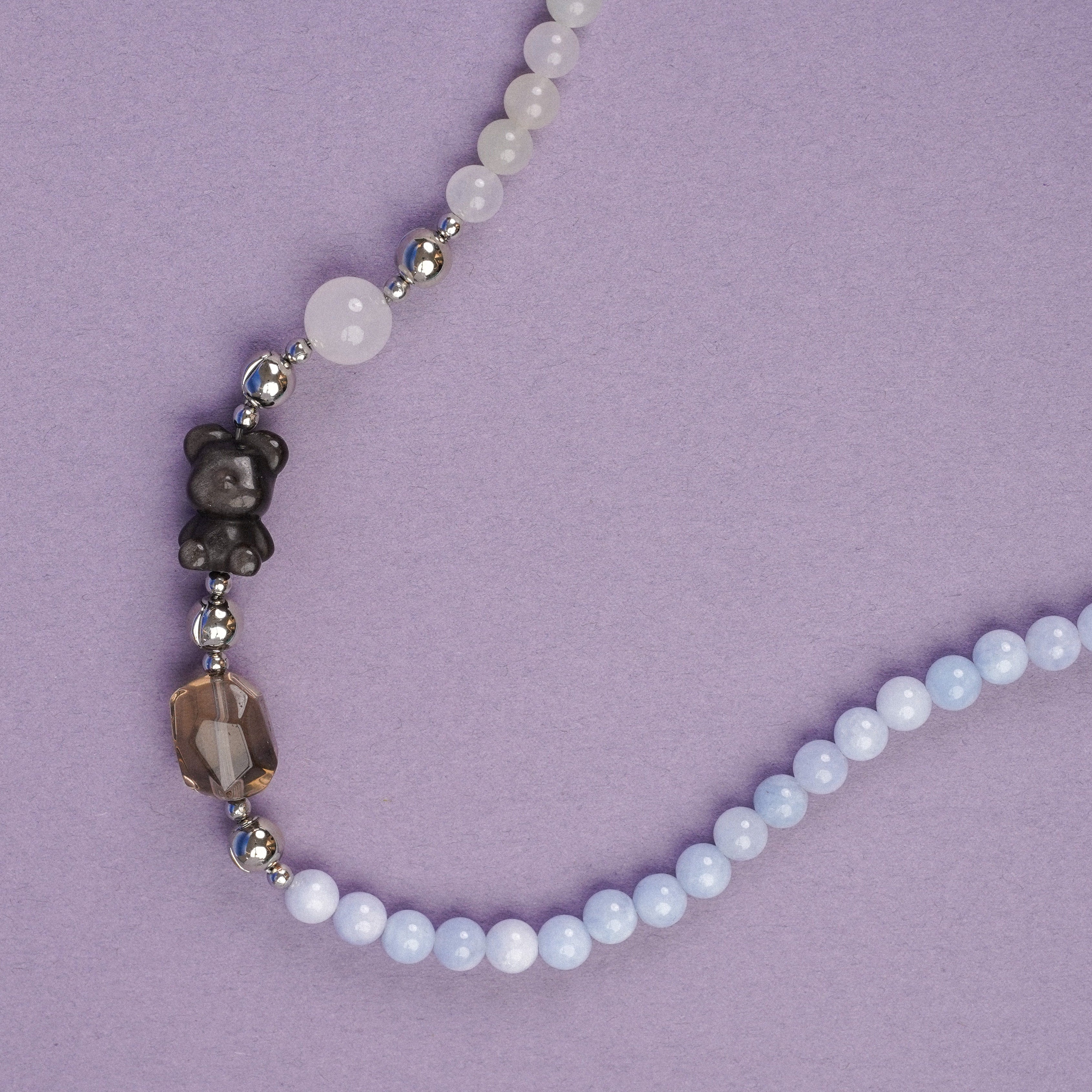 Beaded necklace with white and dark beads on a purple background