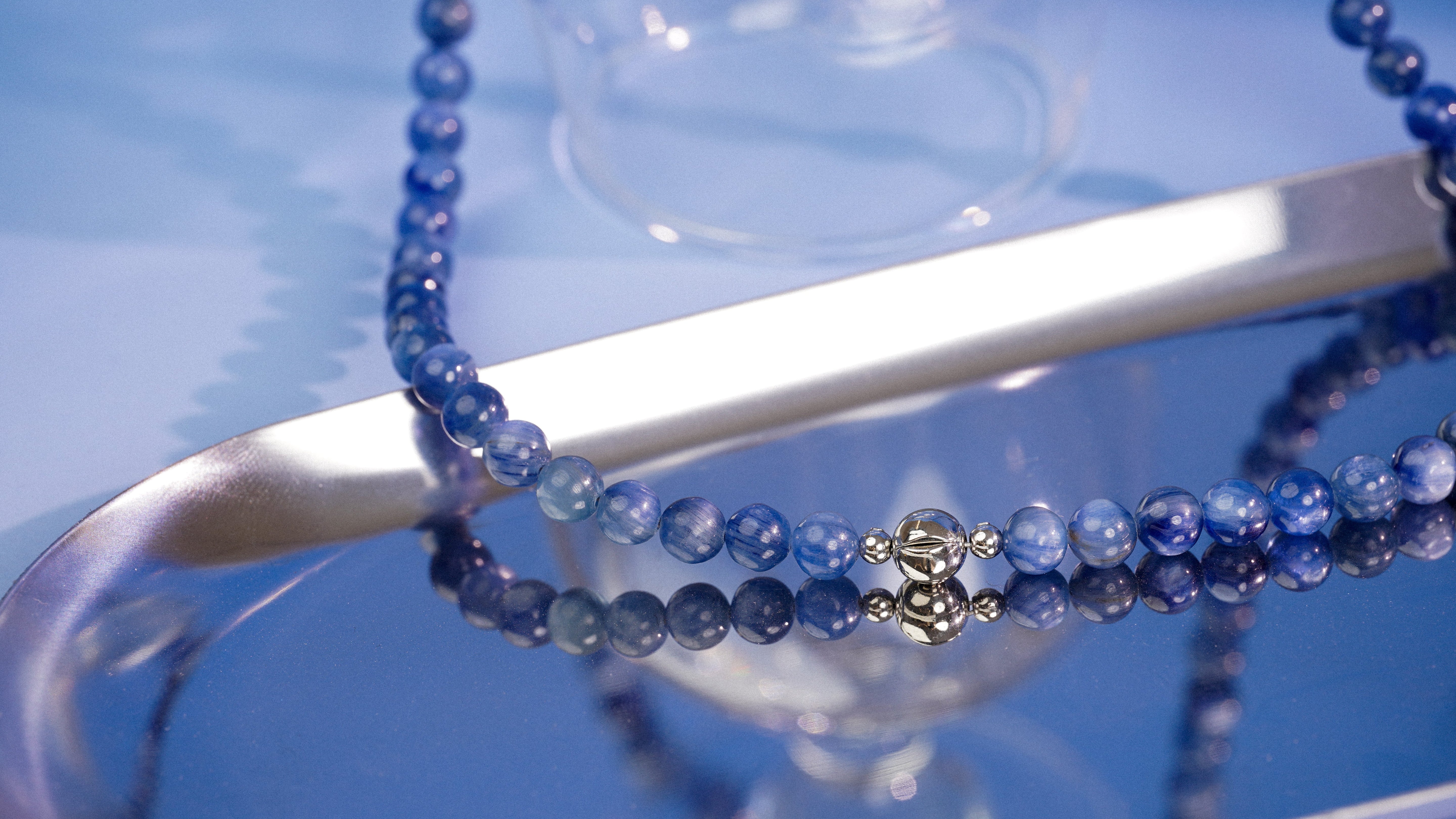 Blue beaded necklace on a reflective surface
