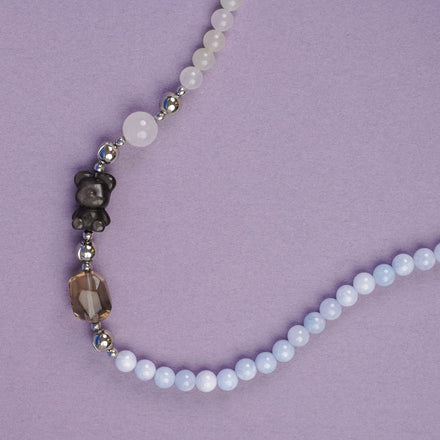 Beaded necklace with white and dark beads on a purple background