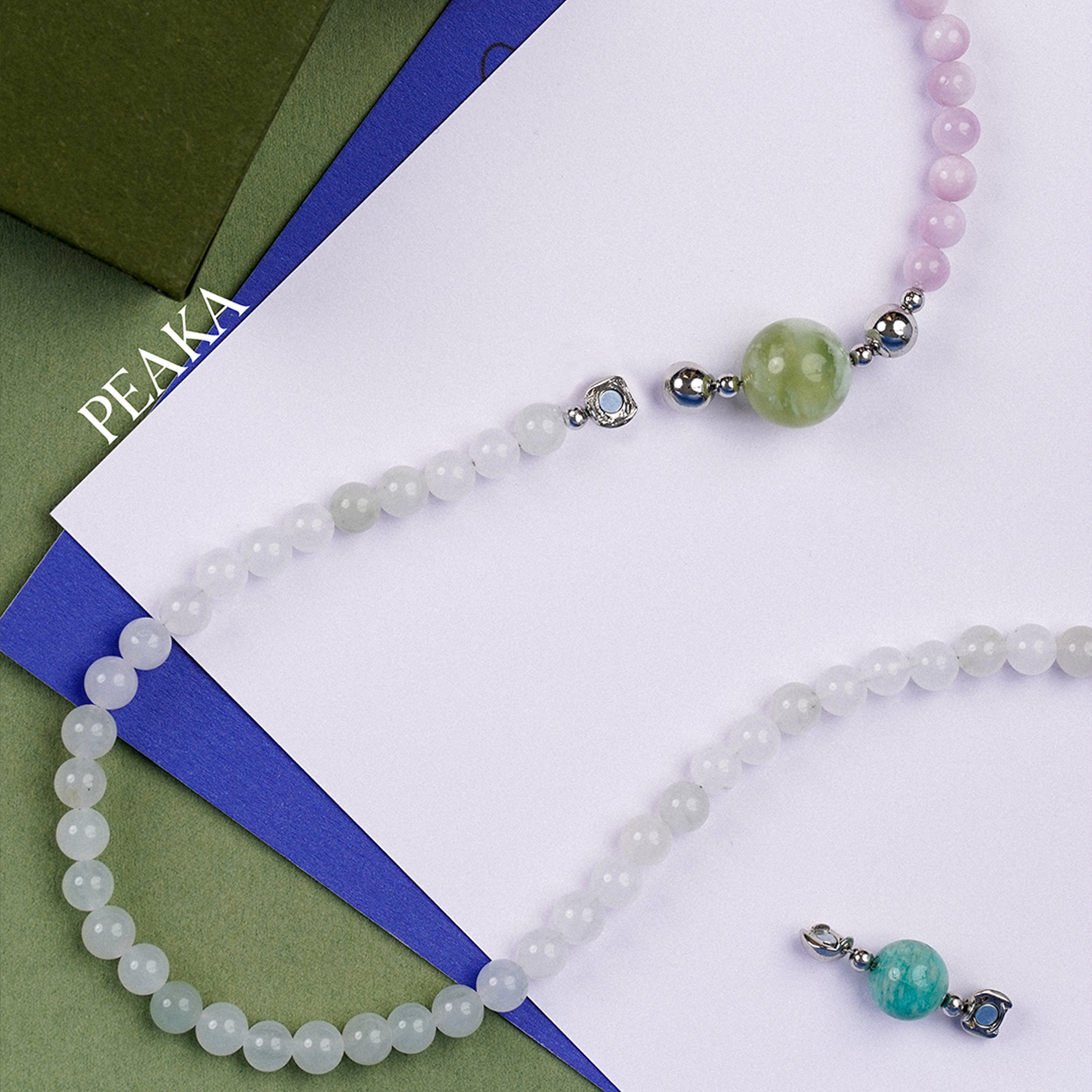 Necklace with pink and green beads on a white and blue striped background